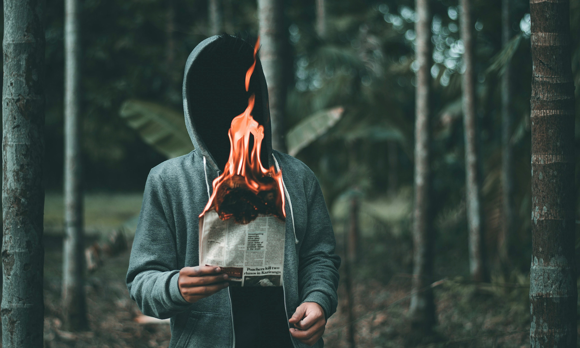 imagem ilustratriva de rapaz branco encapuzado segurando uma folha de jornal em chamas